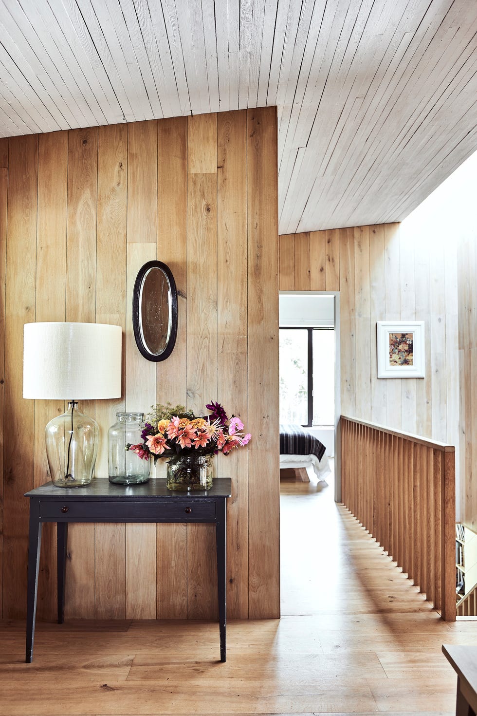 timber clad modern rustic hallway with black minimalistic console table topped with flowers