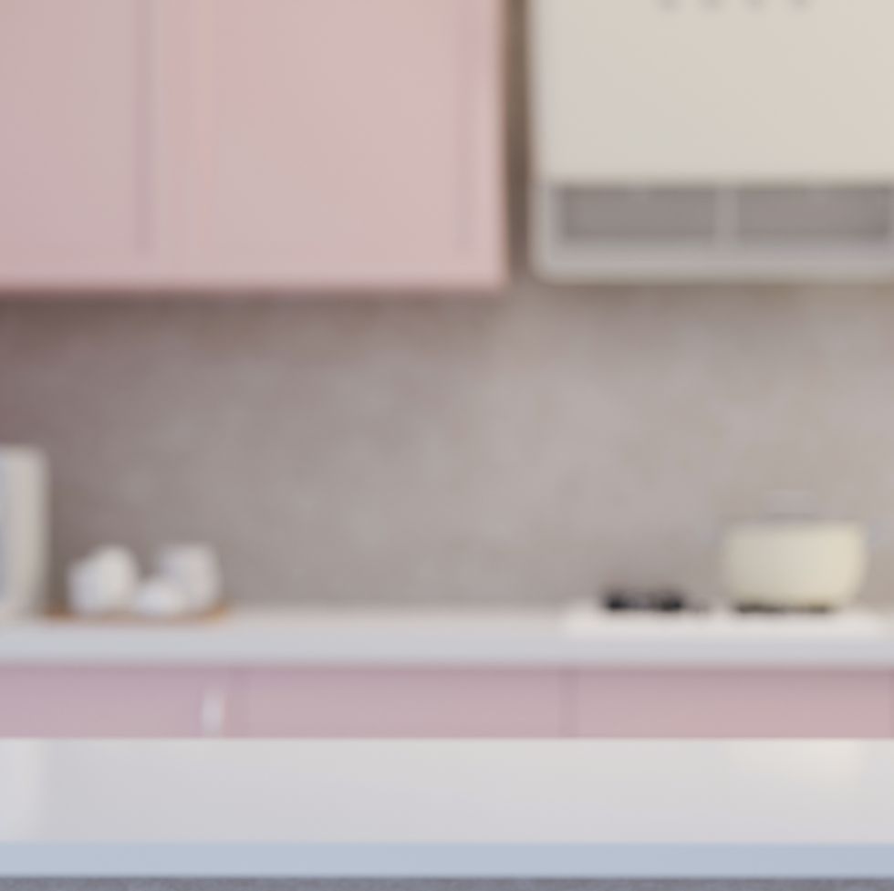 modern white kitchen tabletop with flower vase and copy space over blurred pastel pink kitchen