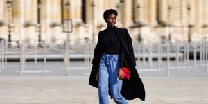 paris, france   march 09 a model wears a black turtleneck wool pullover, a wool black long coat, blue denim jeans, black leather pointy boots, a red bag, outside vuitton, on march 09, 2021 in paris, france photo by edward berthelotgetty images
