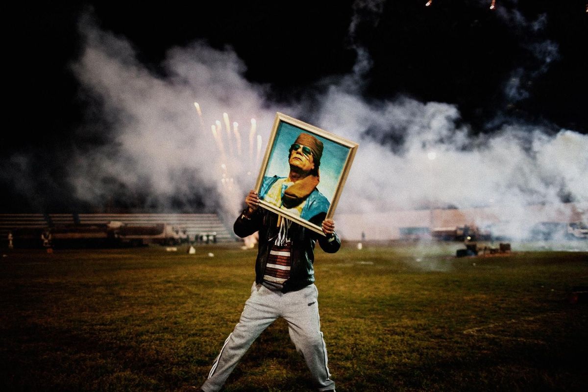Een Khadaffiaanhanger houdt een portret van de Libische leider vast bij een viering die in elkaar is gezet voor een groepje bezoekende buitenlandse journalisten nadat regeringstroepen de stad heroverden op de rebellen Zawiyah Libi Maart 2011