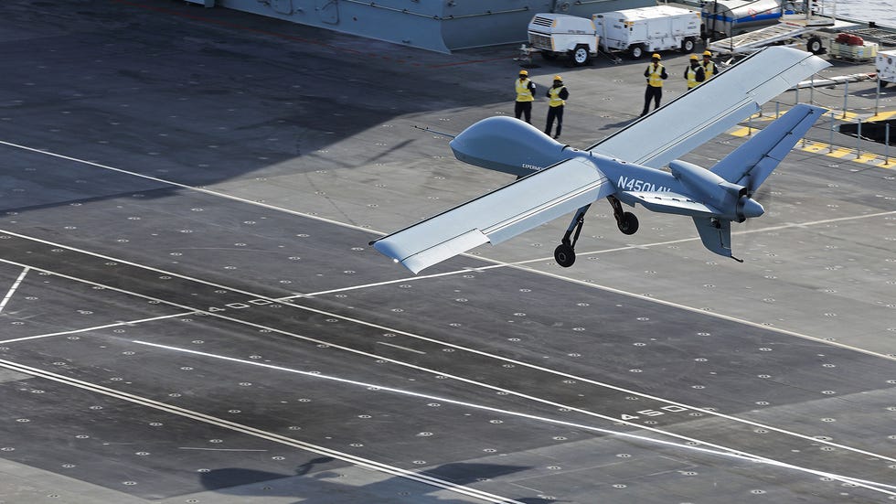 drones taking off from a military deck with personnel observing