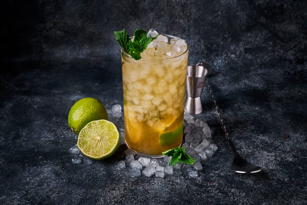 a glass of lemonade with limes and a spoon