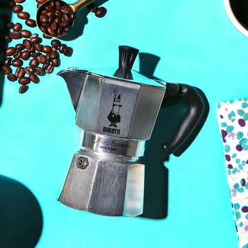 bialetti moka pot with coffee beans and pastry