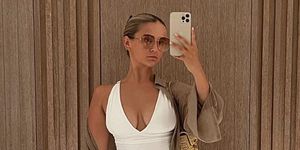 mollymae takes a selfie in a mirror while wearing a white swimsuit