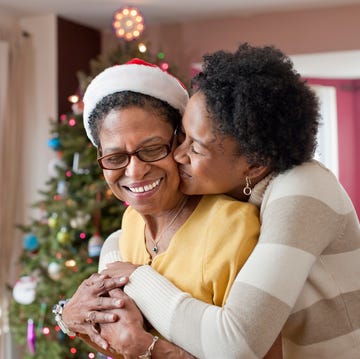 mom and adult daughter hugging at christmas tree