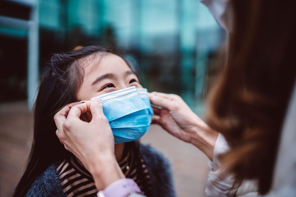 mom helping her daughter to wear medical face mask