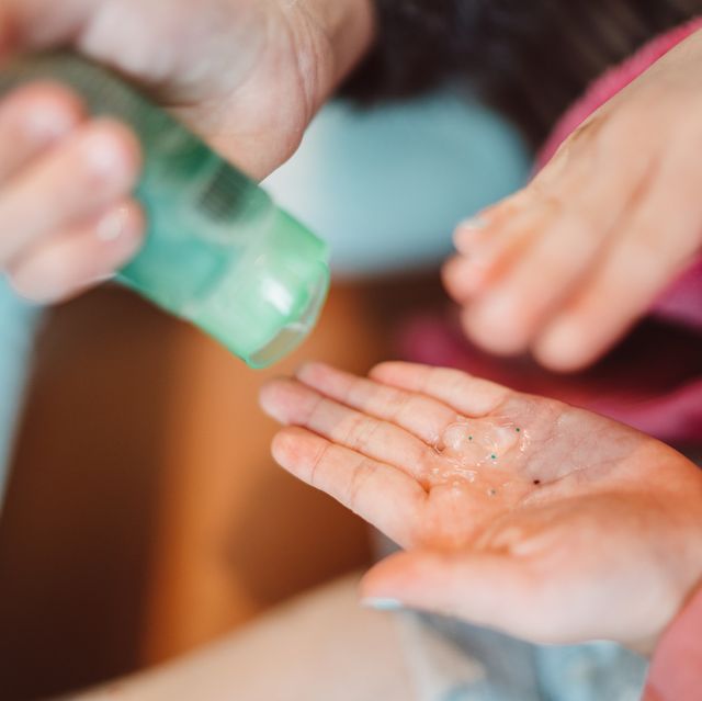 Mom squeezing hand sanitizer onto her littler daughter’s hands