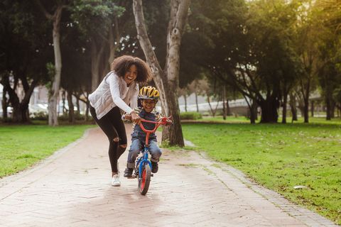 mom teaching her son biking at park