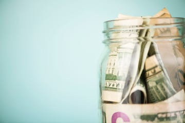 money jar filled with american dollars blue background with space for copy