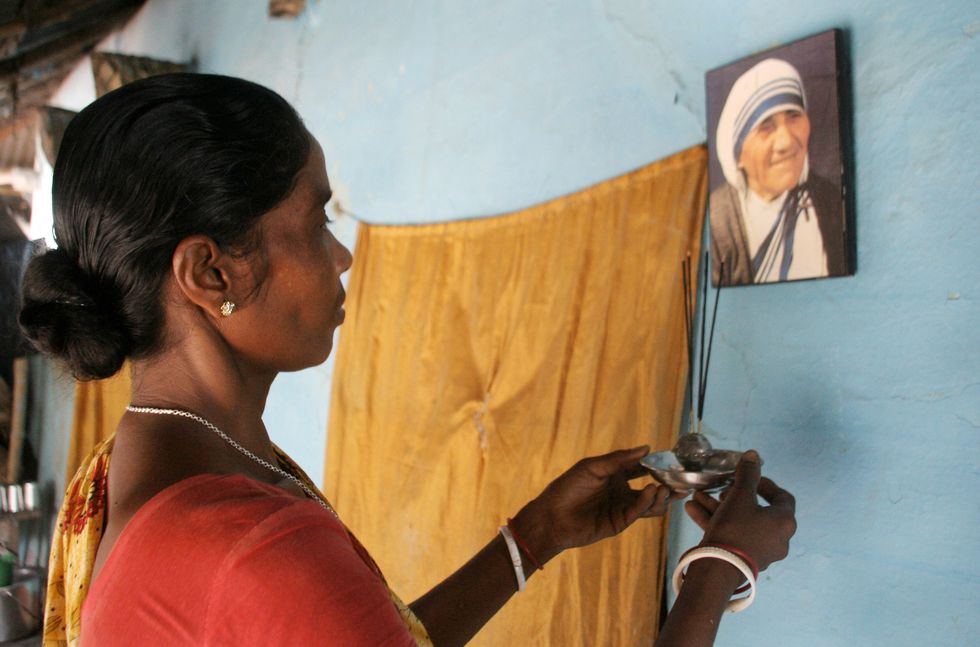 Monica Besra prays in front of a picture of Mother Teresa at her home village of Nakur in Danogram