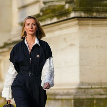 paris, france october 01 a guest wears a white shirt with flared and striped sleeves, a dark jumpsuit, a vuitton brown bag shaped as a cylinder, earrings outside louis vuitton, during paris fashion week womenswear spring summer 2020, on october 01, 2019 in paris, france photo by edward berthelotgetty images