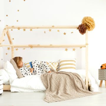 young kid reading in house frame montessori bed