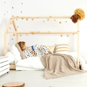 young kid reading in house frame montessori bed