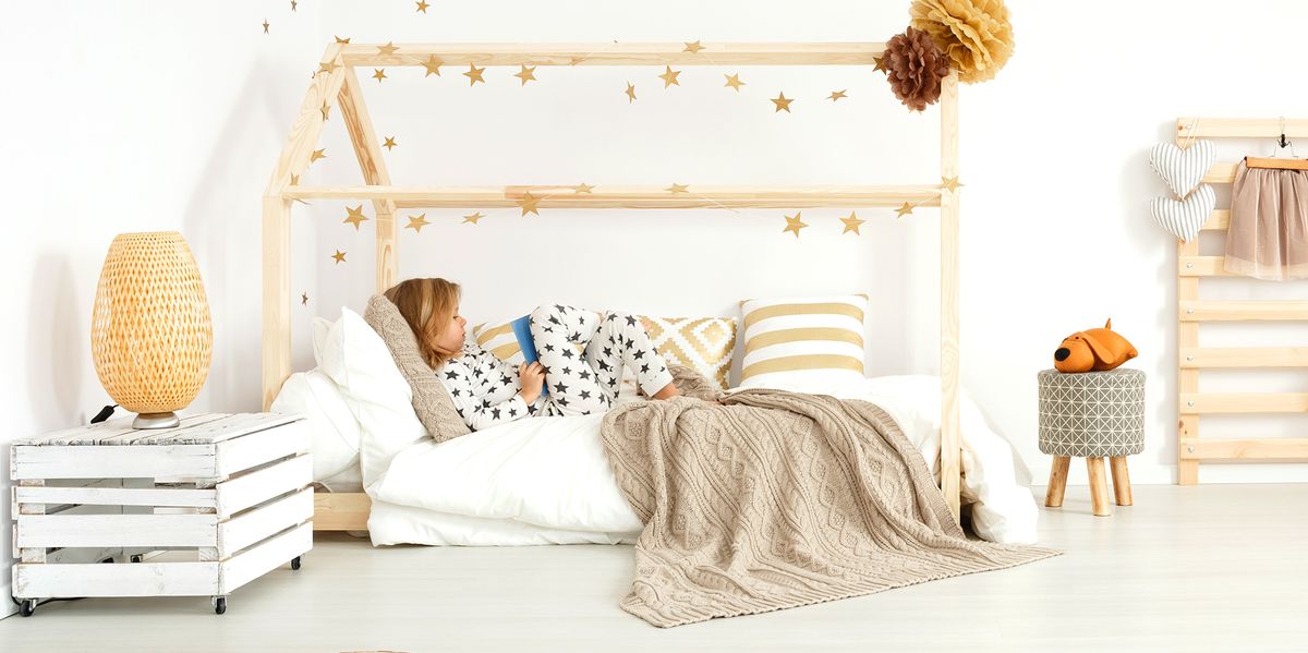 young kid reading in house frame montessori bed