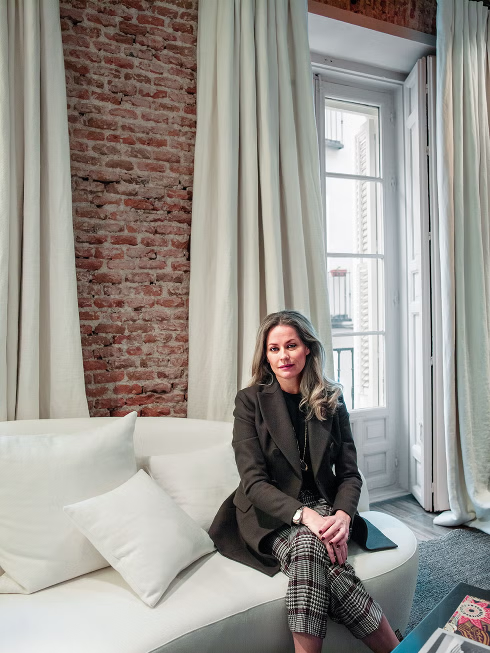 a person seated on a curved white sofa in a room with exposed brick walls
