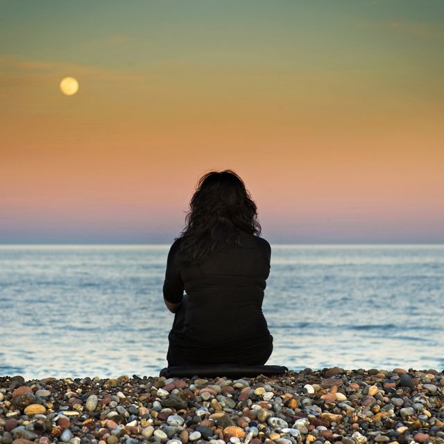 one woman sitting at beach and sky with moon in spain