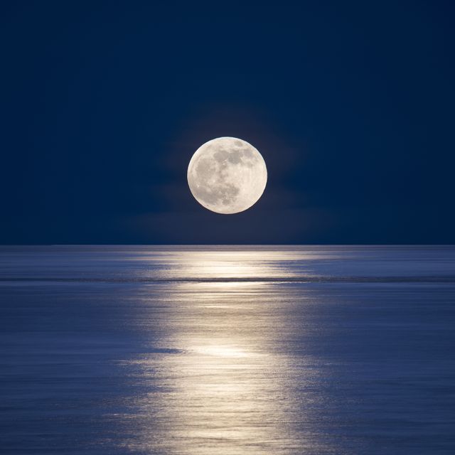 full moonrise over calm sea with moonlight on water