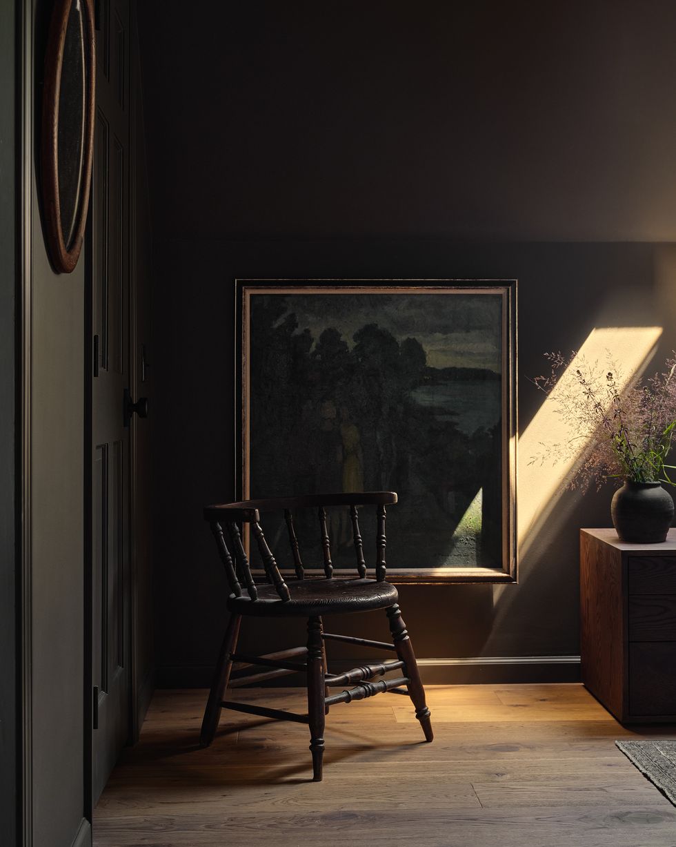 corner of a bedroom with a chair and a painting on the wall