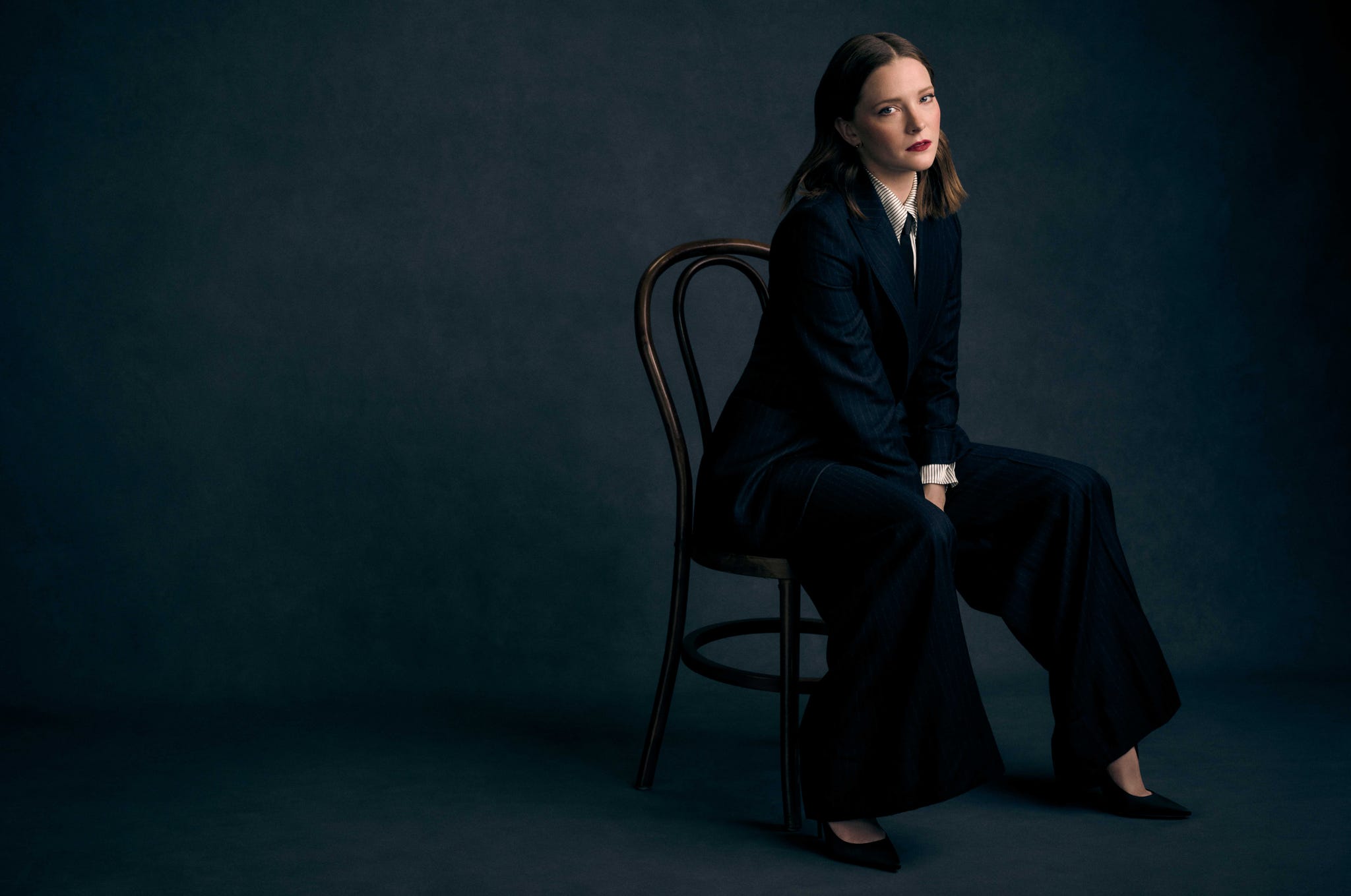 morfydd clark sitting on a chair