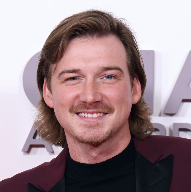 morgan wallen posing for a photo in front of a red carpet backdrop at the cma awards