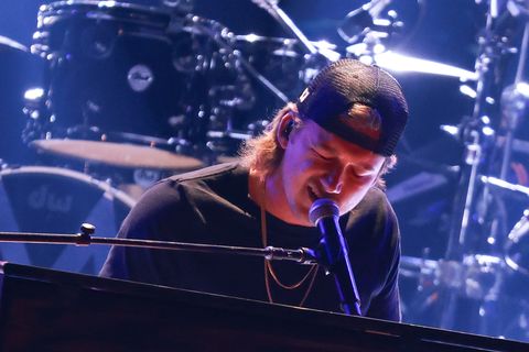 morgan wallen singing into a microphone and playing the piano