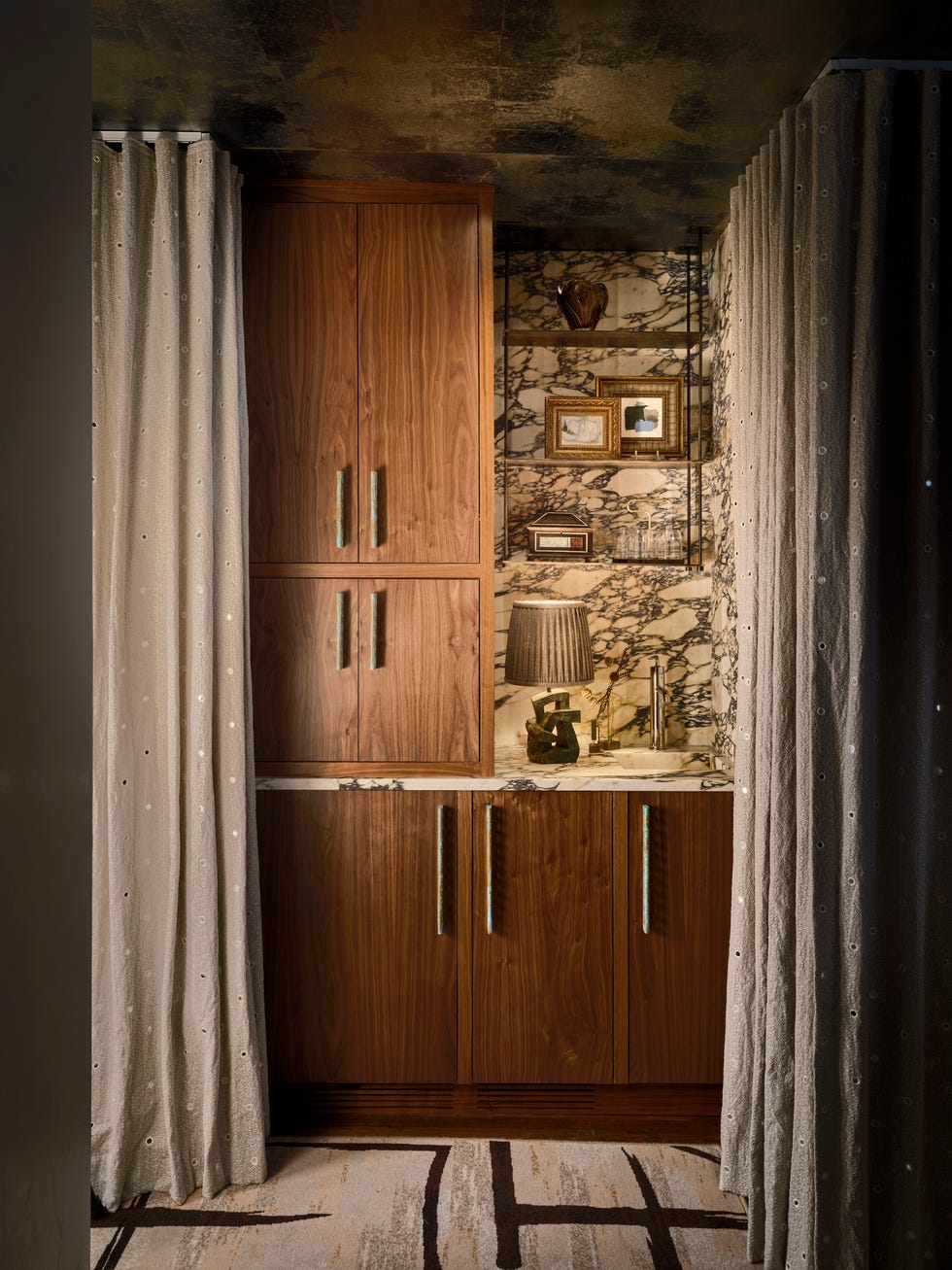 a home bar with wood cabinets and curtains