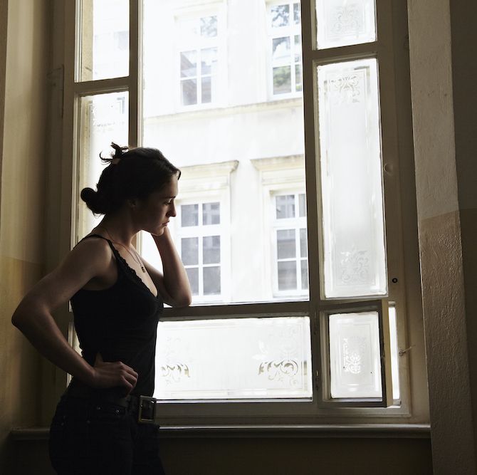 morning anxiety young woman standing in a stairway looking outside the window