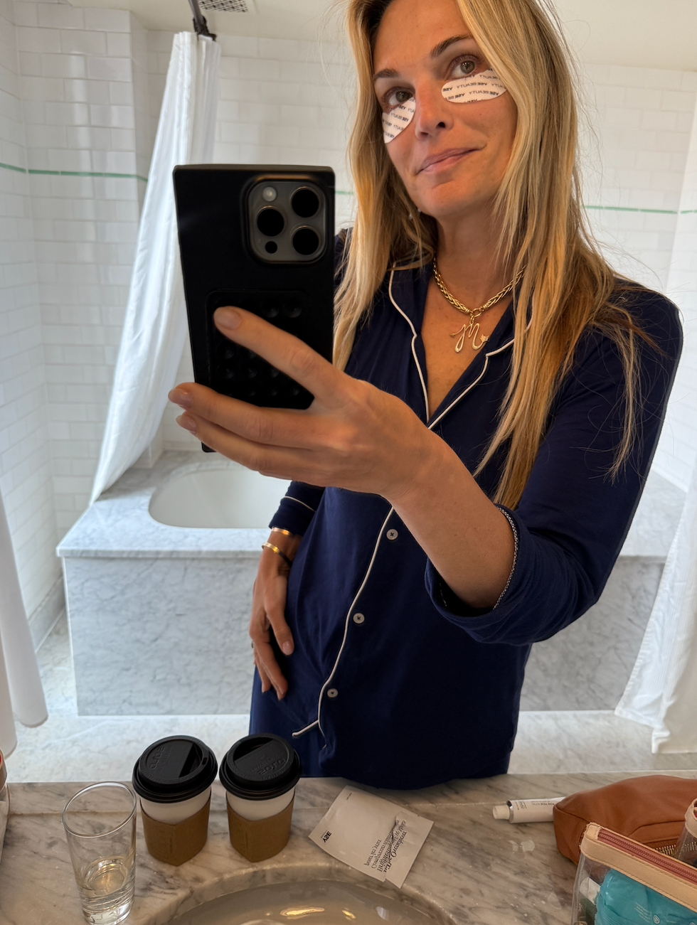 molly sims taking a self portrait in a bathroom showcasing coffee cups and personal items