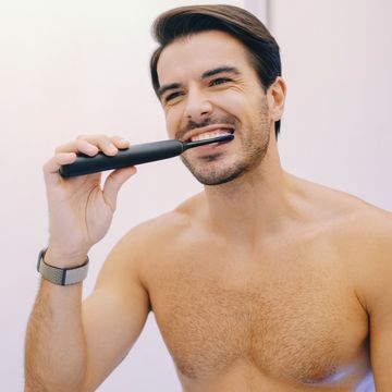 hombre lavándose los dientes con cepillo de dientes eléctrico