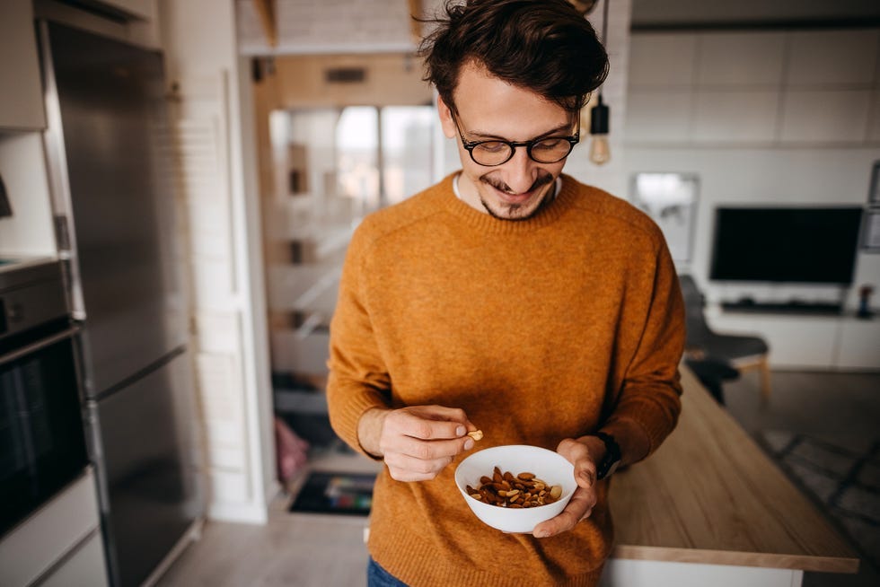 person holding a bowl of nuts in a kitchen