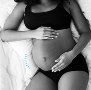 a pregnant woman holding her belly in bed