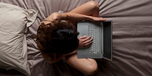 a person lying on a bed with a laptop