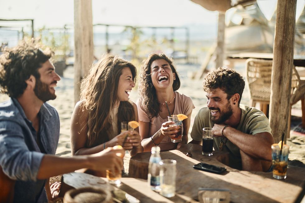 group of cheerful friends communicating while spending a summer day in a beach cafe