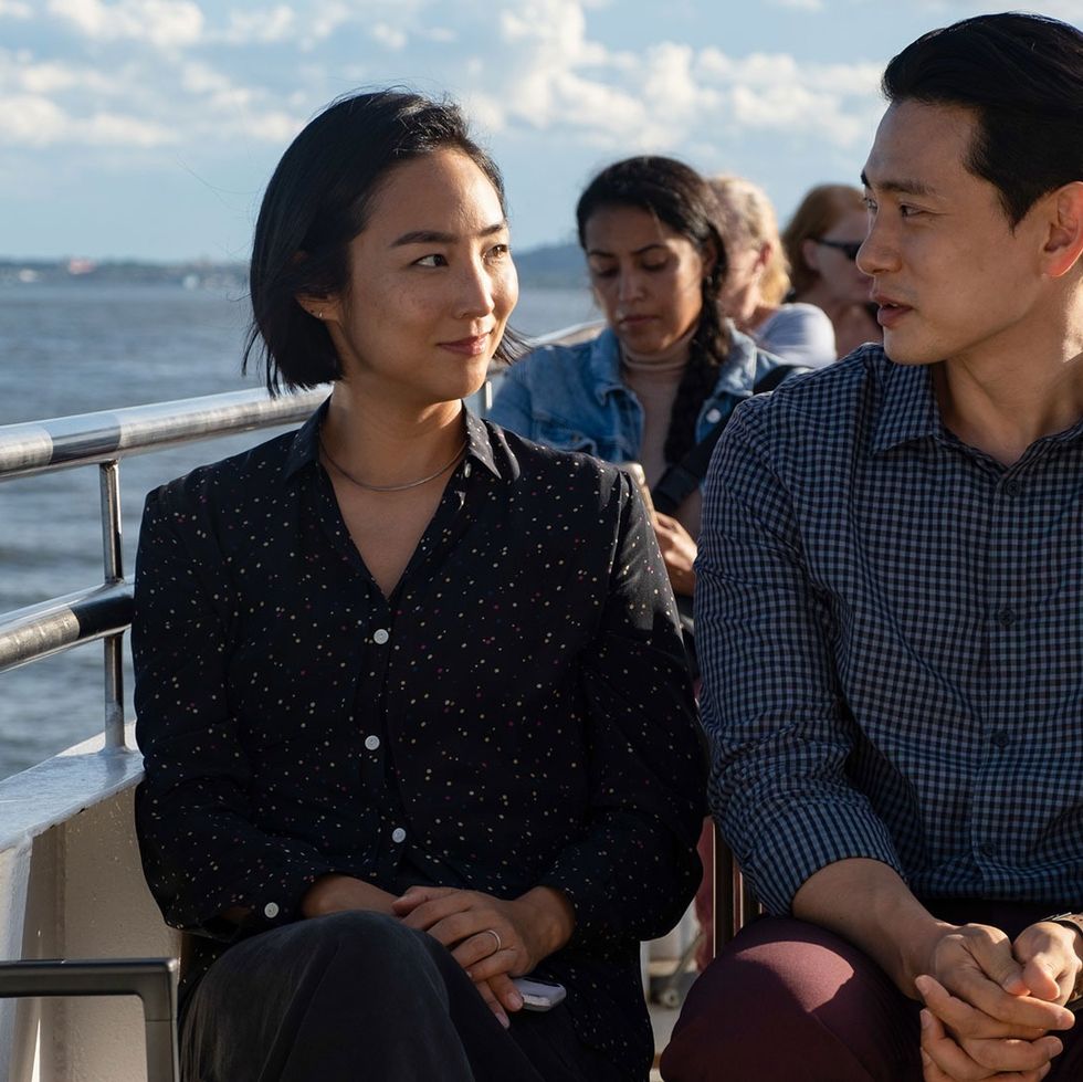 two people look at each other longingly while riding on a ferry in a scene from past lives