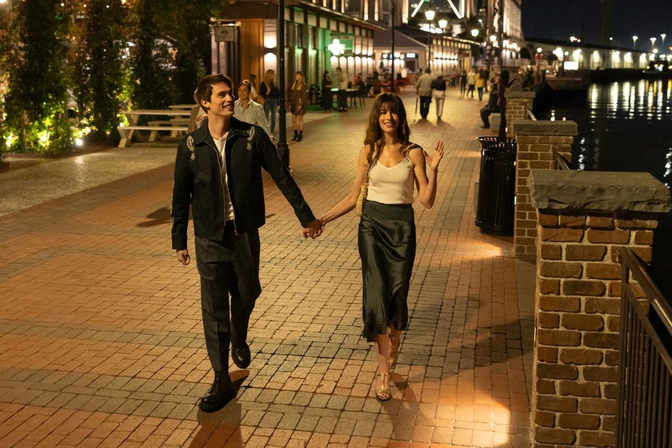 a couple walks down the street at night while holding hands in a scene from the idea of you