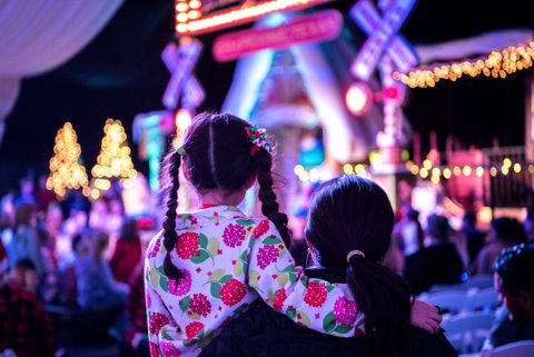 mother and child are waiting for santa at a christmas tree lighting ceremony