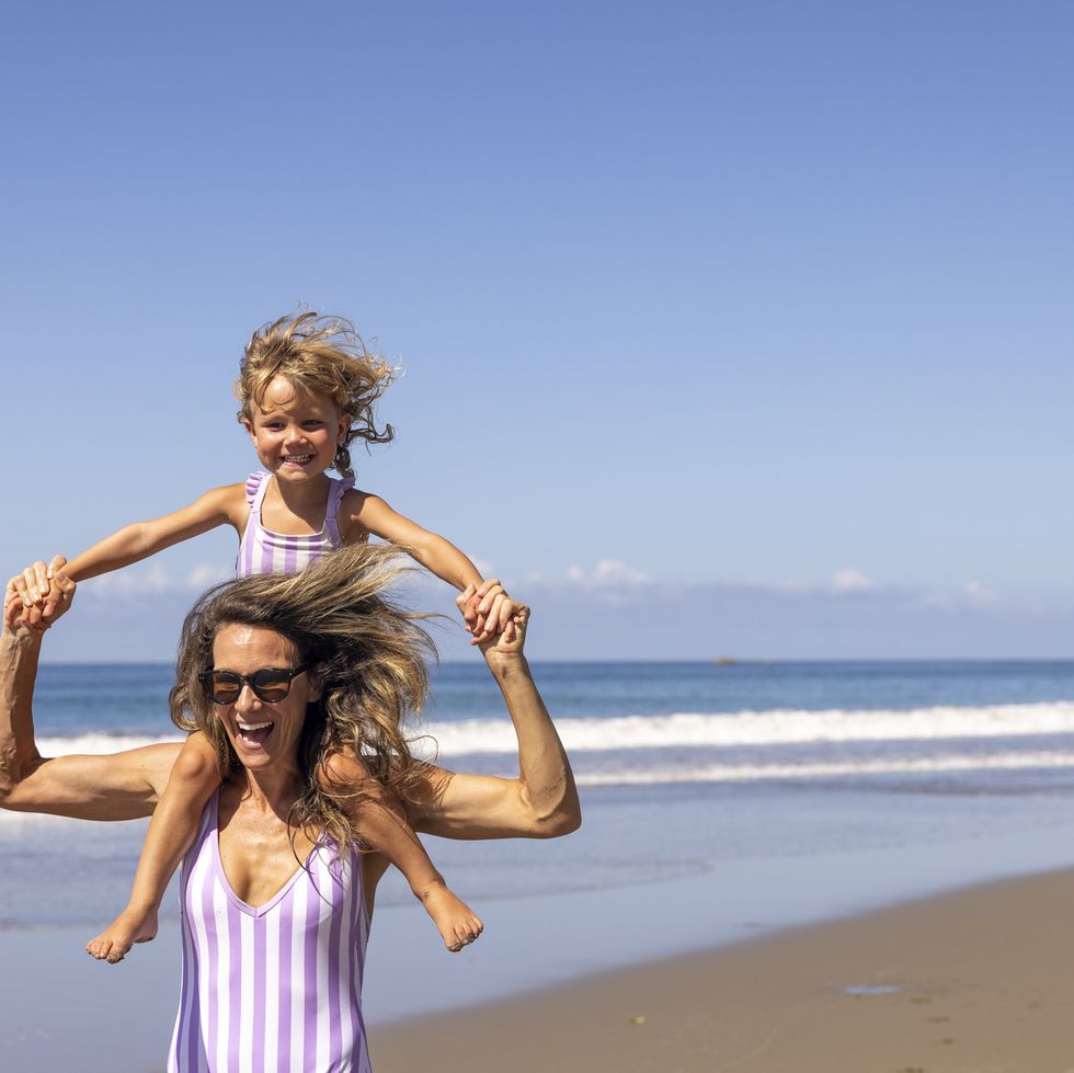 matching swimsuits mother and daughter running on beach