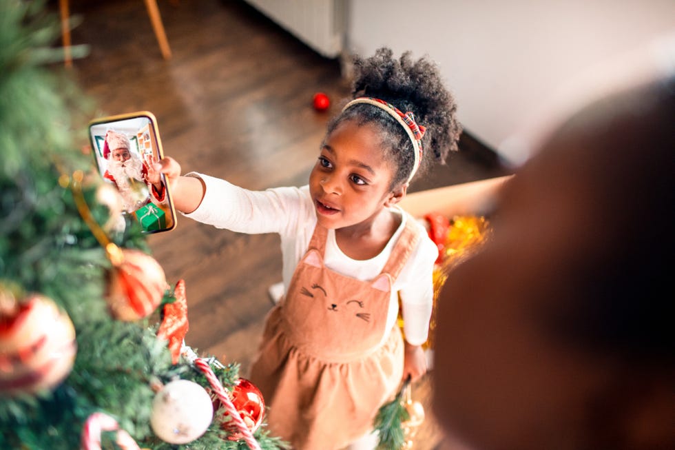 mother and daughter on a video call with santa claus while decorating the christmas tree