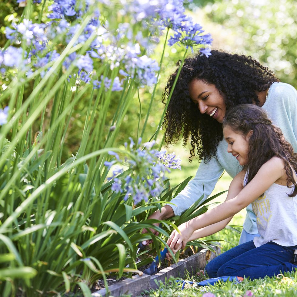 mother and daughter planting flowers in garden