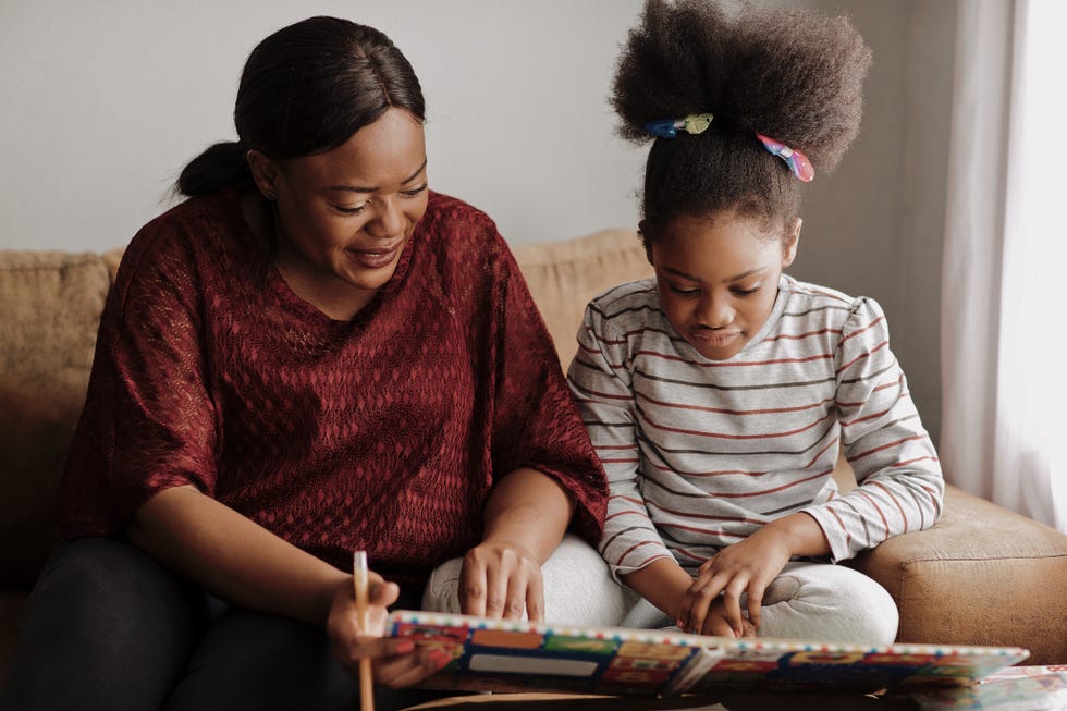 mother and daughter reading a children's book on the couch