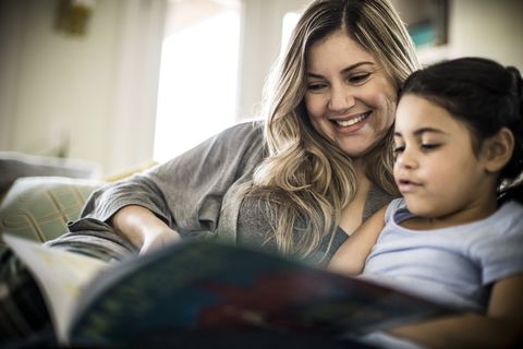mother and daughter 7yrs reading book on couch
