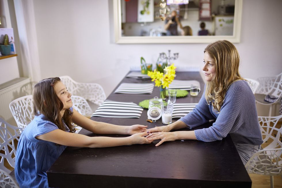Mother and daughter sitting face to face at dining table