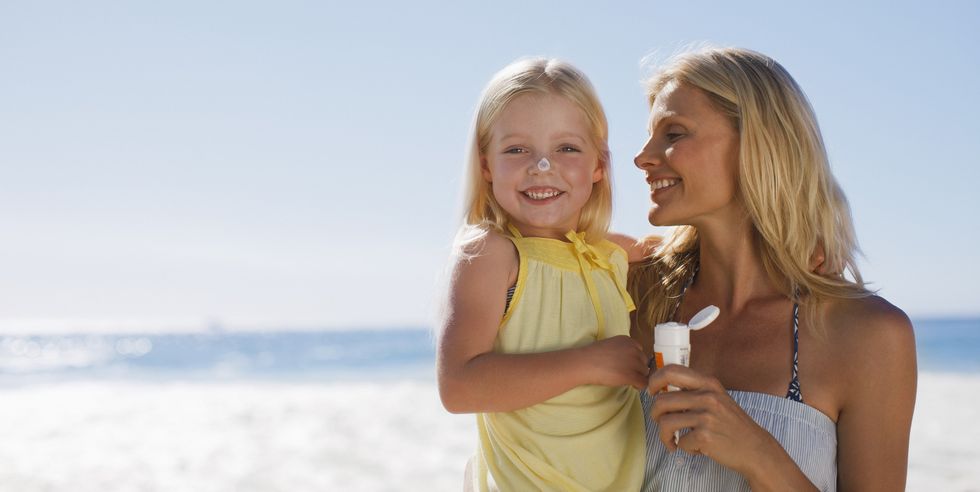 mother and daughter with sunscreen on beach