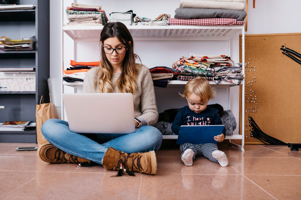 mother and little daughter sitting on the floor at home using laptop and tablet