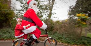mother and son dressed as santa claus on a bicycle