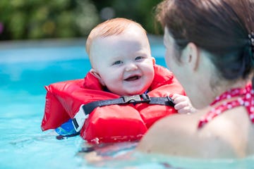 madre con hijo con chaleco jugando en piscina