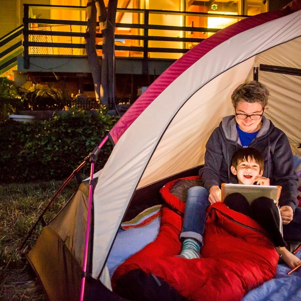 staycation ideas - Mother and son using digital tablet in backyard tent