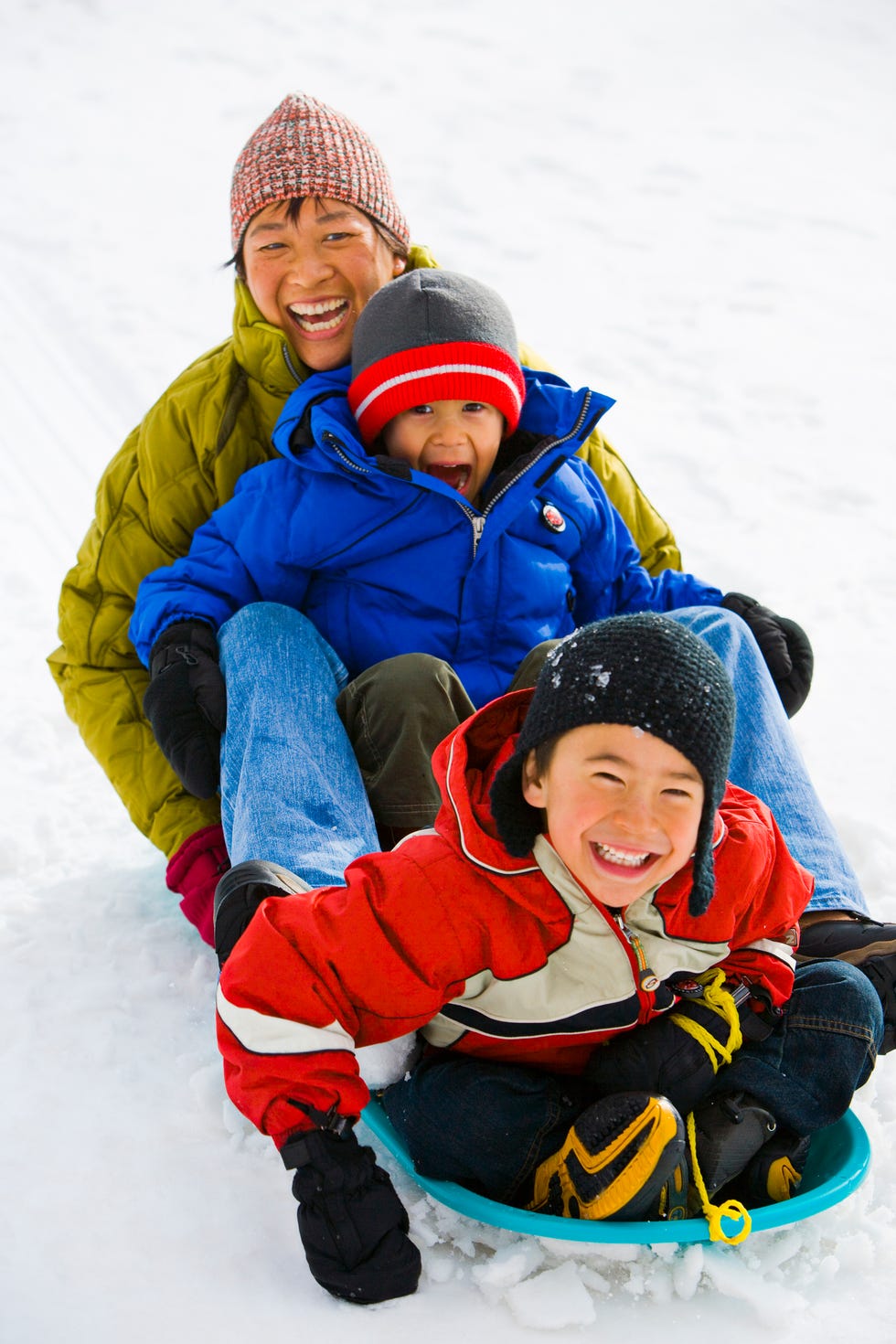 mother and two son 4 6 sledding down hill, laughing, elevated view