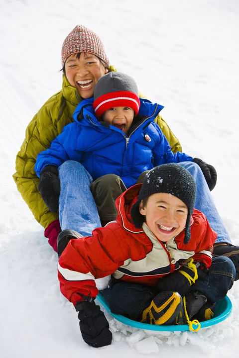 mother and two son 4 6 sledding down hill, laughing, elevated view