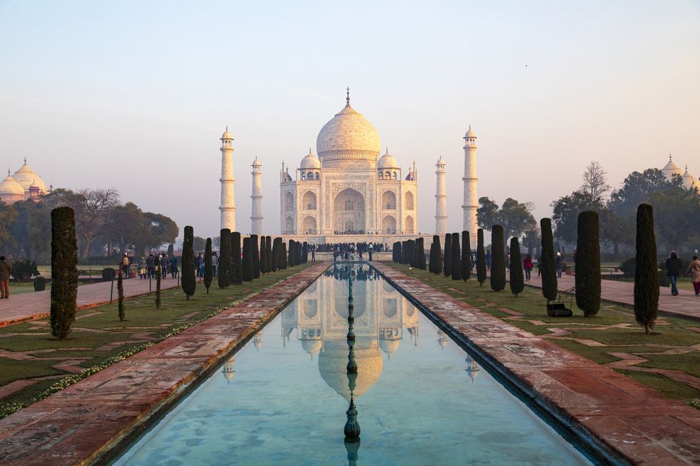 captured in the early morning light, this image showcases the taj mahal as its rarely seen, bathed in the warm glow of the rising sun with minimal haze, the iconic white marble monument stands in sharp contrast to the sky, fully revealing its intricate design and grandeur the photograph captures a tranquil moment at one of the worlds most celebrated landmarks, offering a unique perspective of the taj mahals timeless beauty